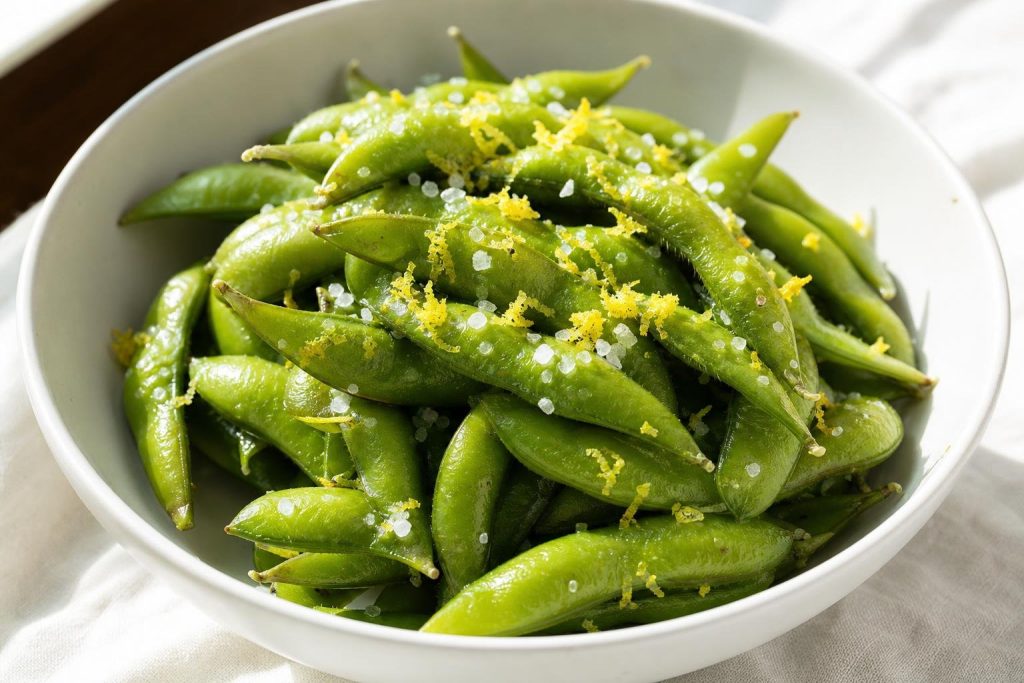 Steamed Japanese edamame pods sprinkled with sea salt and lemon zest in a white bowl
