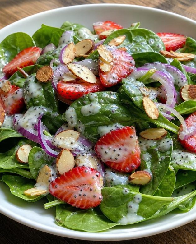 Bowl of spinach and strawberry salad with sliced almonds and poppy seed dressing