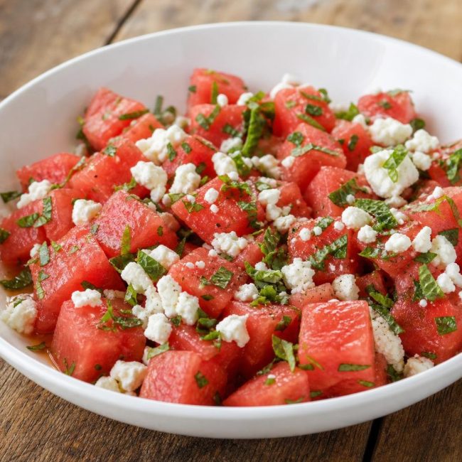 Bowl of watermelon feta and mint salad with lime vinaigrette showing watermelon cubes, crumbled feta, and chopped mint.